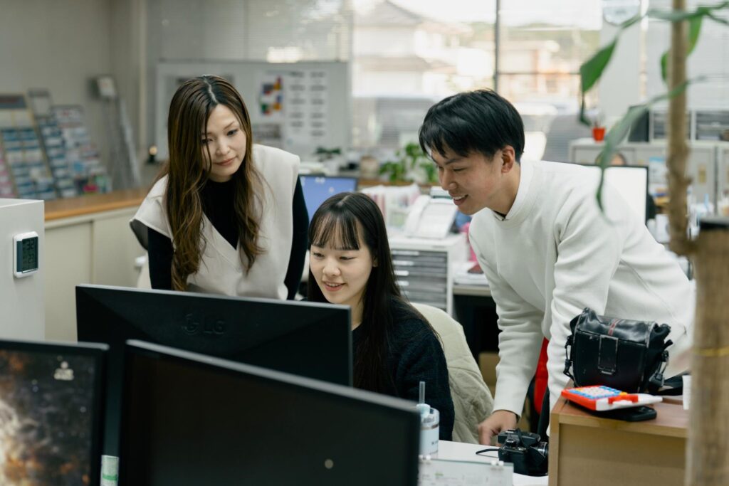 パソコンを見ながら話し合いをする社員の画像